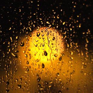 Light shining through a window speckled with rain